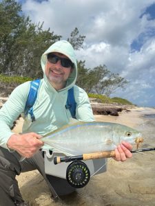 Fly angler holding a bar jack caught on foot along a remote beach in Grand Cayman, Cayman Islands
