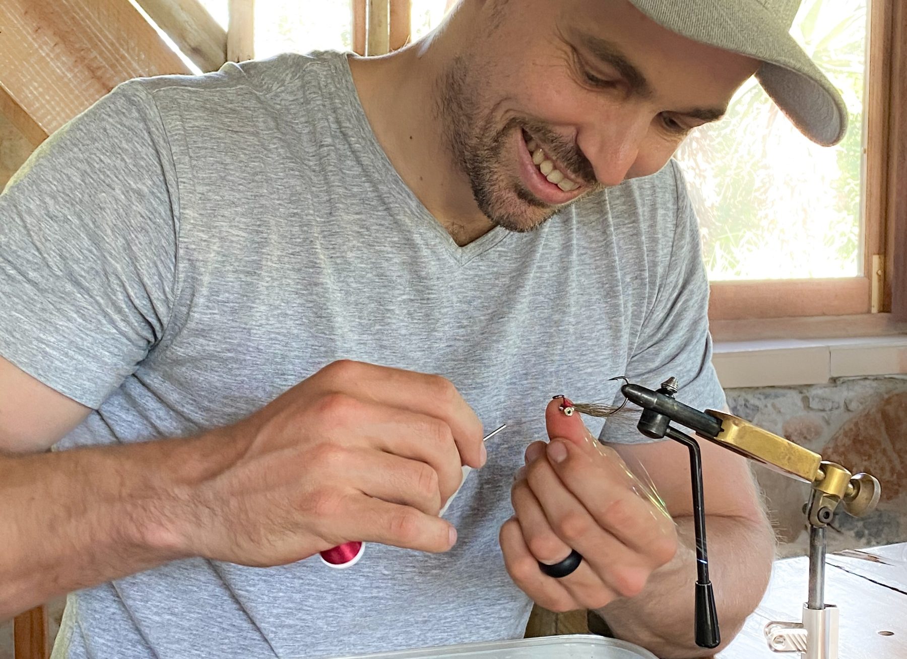 Angler tying bonefish fly at a vise in natural light setting in Grand Cayman, Cayman Islands