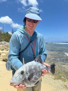 Angler holding a triggerfish caught fly fishing along the rocky shoreline in Grand Cayman, Cayman Islands