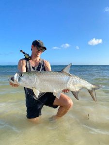 Local fly fishing guide holding a tarpon caught sight fishing in shallow water at the best tarpon spot in Grand Cayman, Cayman Islands