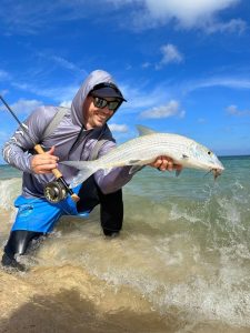 Fly angler holding a bonefish on a Grand Cayman flat often targeted by local guides and DIY fishermen alike