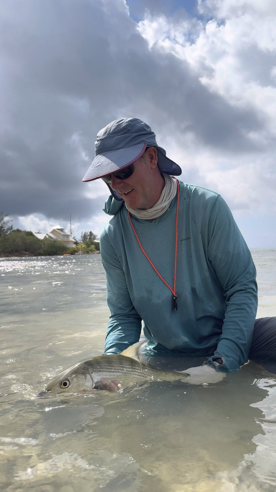 Fly fisherman releasing a bonefish caught fly fishing in shallow water on the flats in Grand Cayman, Cayman Islands