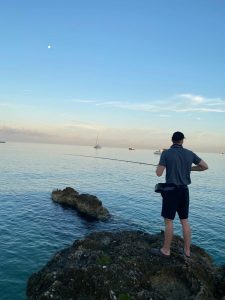 Fly fisherman looking for tarpon at sunrise from a rocky shoreline in Grand Cayman, Cayman Islands