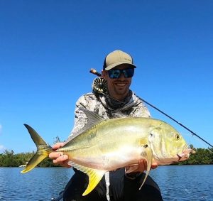 Fly fishing angler holding a jack crevalle caught in calm inshore waters with help from the best guide in Grand Cayman, Cayman Islands