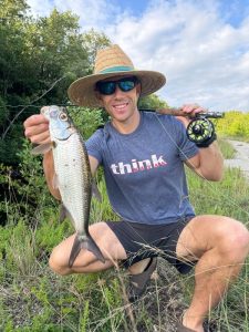 Fly angler holding a juvenile tarpon caught in the canals at one of the best tarpon spots in Grand Cayman, Cayman Islands