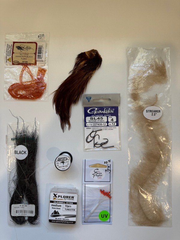 Fly tying materials laid out for the best bonefish flies, including craft fur, hooks, rubber legs, and UV thread for fly fishing in Grand Cayman, Cayman Islands