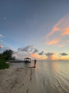 Silhouetted fly angler casting at tailing bonefish at sunset in Grand Cayman, Cayman Islands