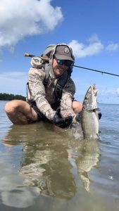 Fly angler landing a bonefish in shallow water at the best bonefish spot in Grand Cayman, Cayman Islands - a spot often targeted by local guides and self-guided fishermen alike